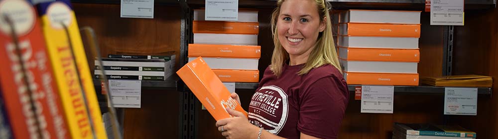 Smiling student holding book while in the WCC bookstore