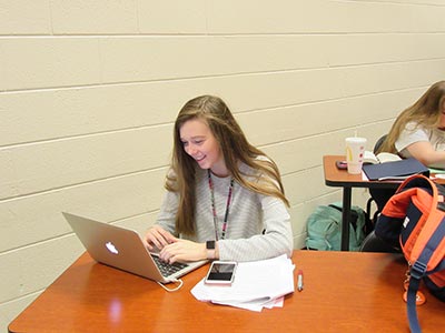 Smiling female student using laptop