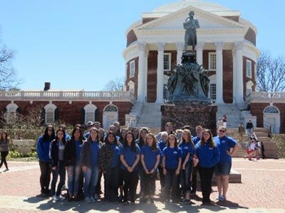 group of student posing in front of a statue on a college campus